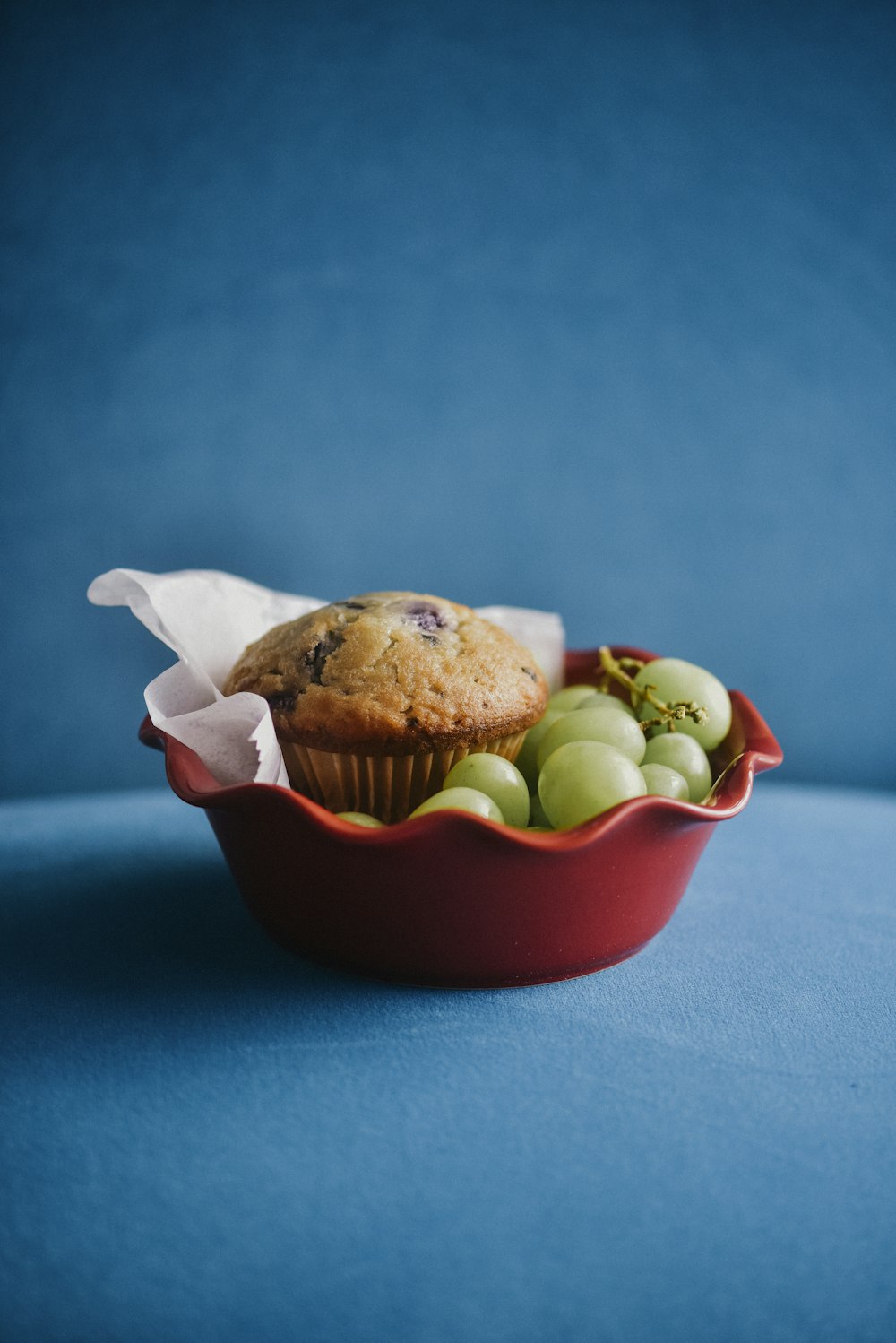 a muffin in a red bowl filled with fruit