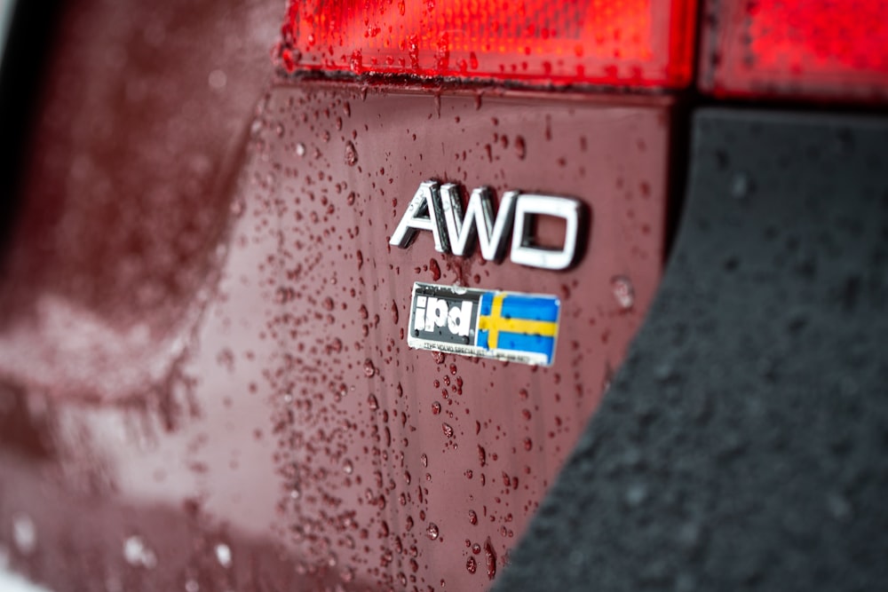 a close up of a red car with rain drops on it