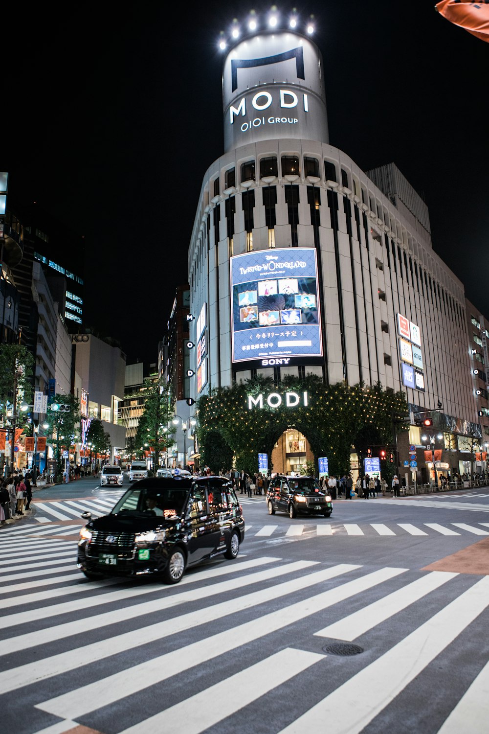 a busy city street at night with cars and people