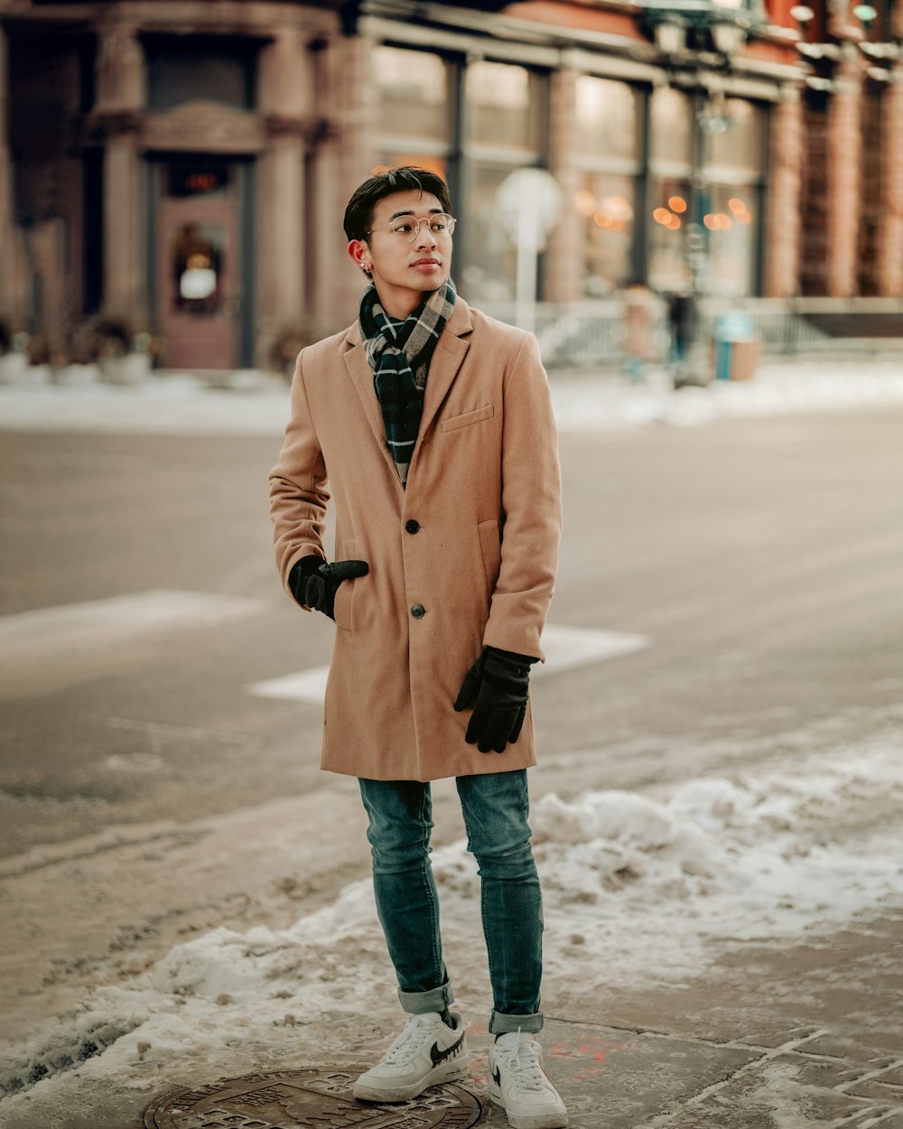 a man standing on the side of a road wearing a coat