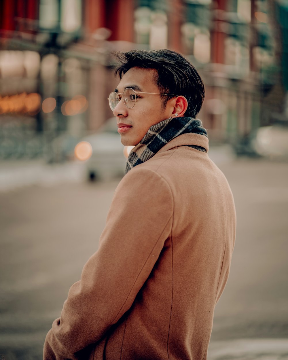 a man with glasses standing on a street corner