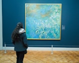 A close-up of a vibrant impressionist painting displayed in a softly lit gallery space.