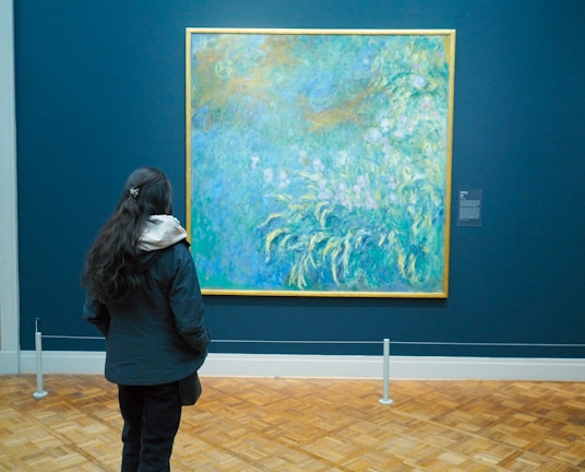 A close-up of a vibrant impressionist painting displayed in a softly lit gallery space.