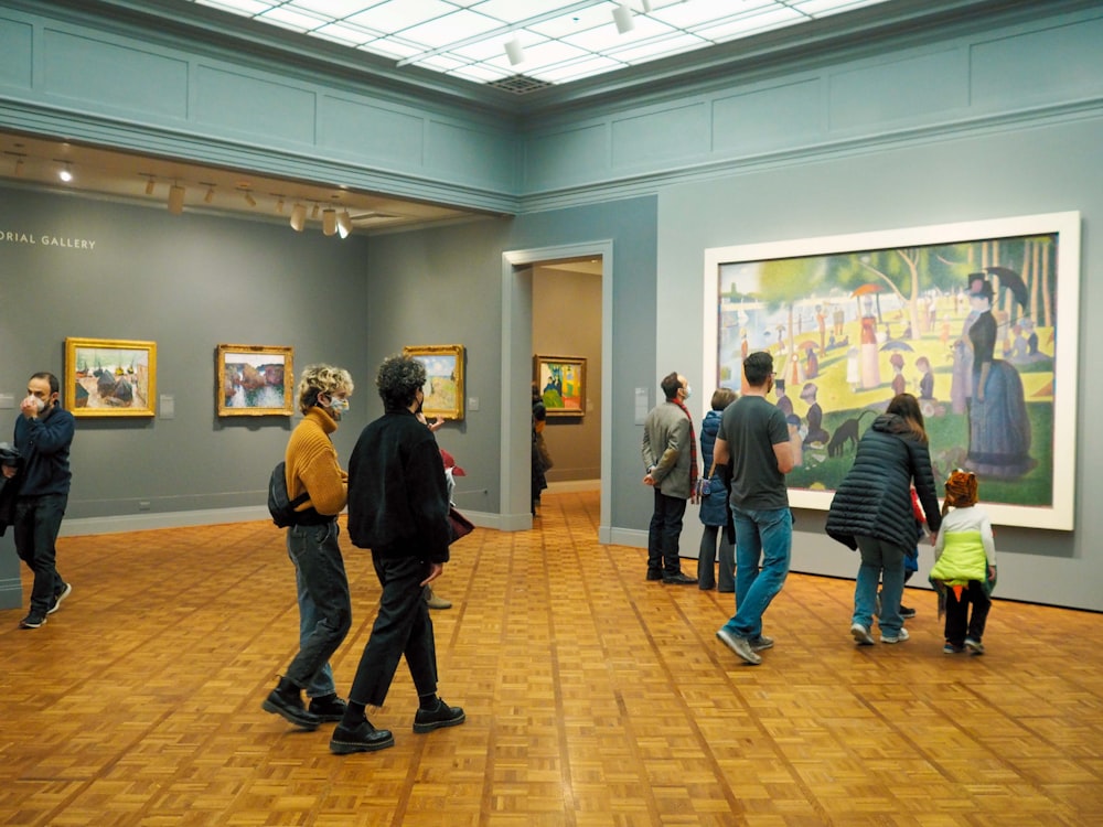 a group of people standing in a museum looking at paintings