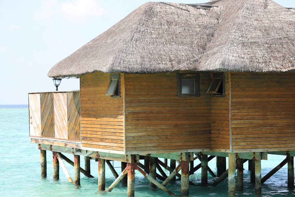 a wooden structure with a thatched roof in the ocean