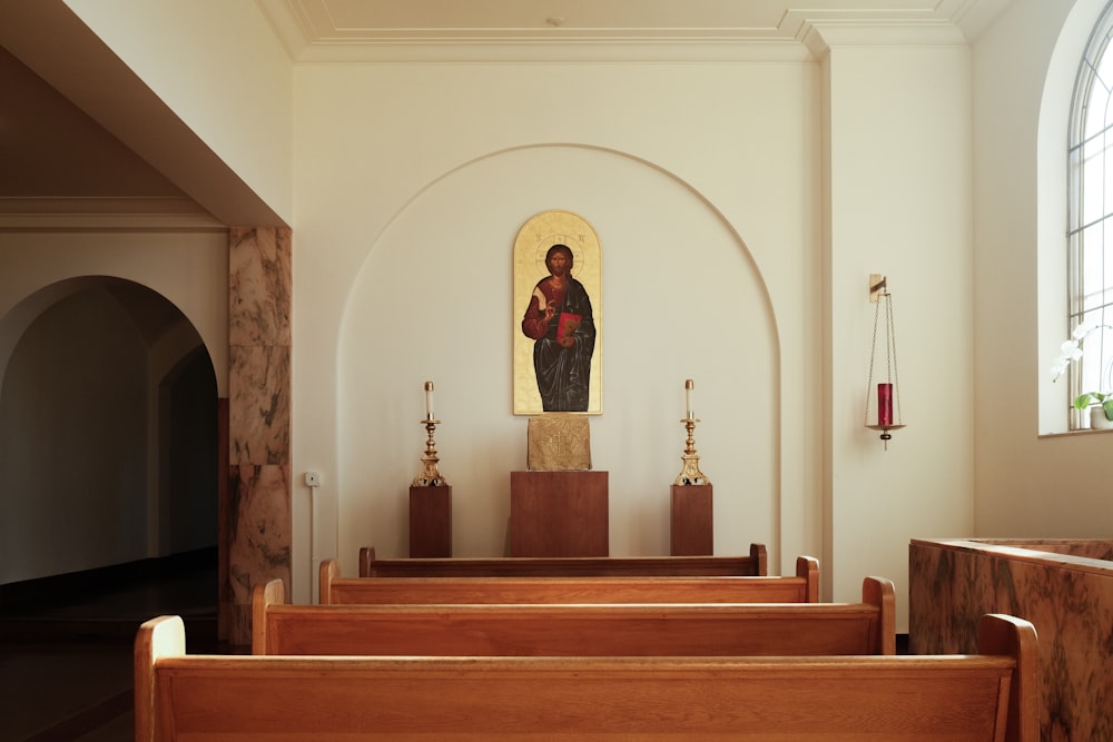 a church with wooden pews and a painting on the wall