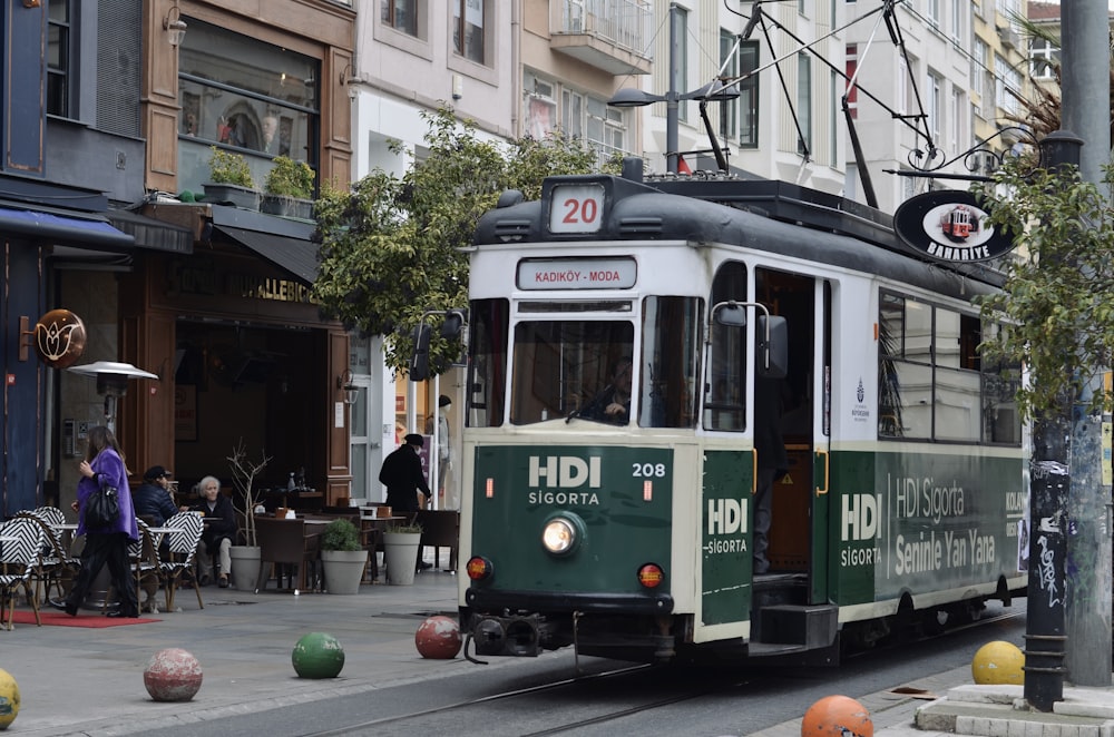 a green and white trolley on a city street