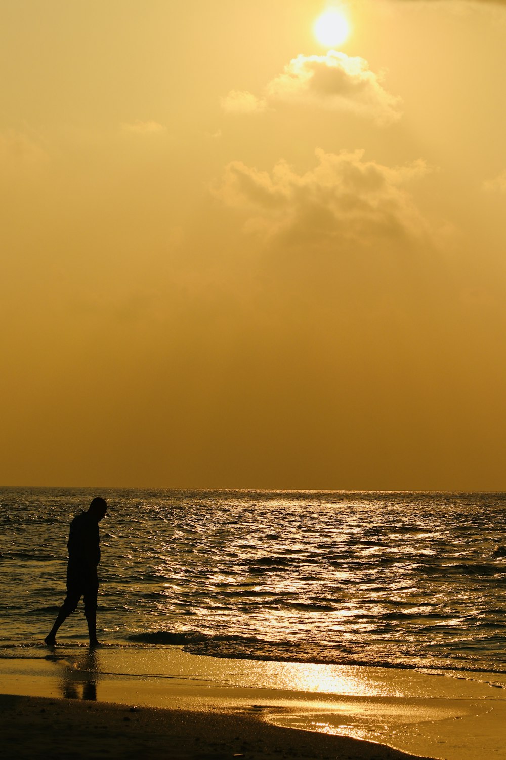 une personne marchant sur la plage au coucher du soleil