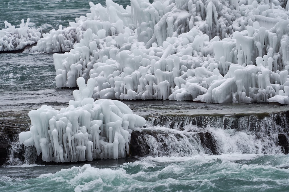 a waterfall covered in ice next to a body of water