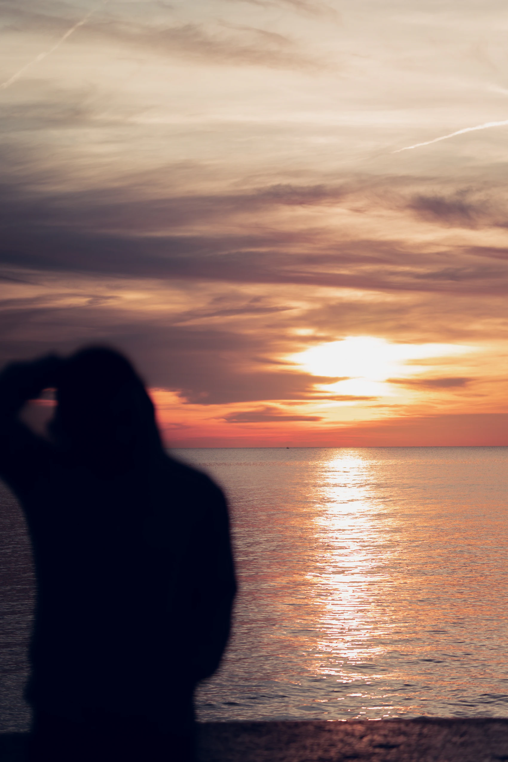 A person silhouetted against the sunrise on Barcelona's Barceloneta beach