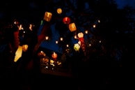 A cozy outdoor patio illuminated by several moonlight bamboo lanterns hanging from tree branches.