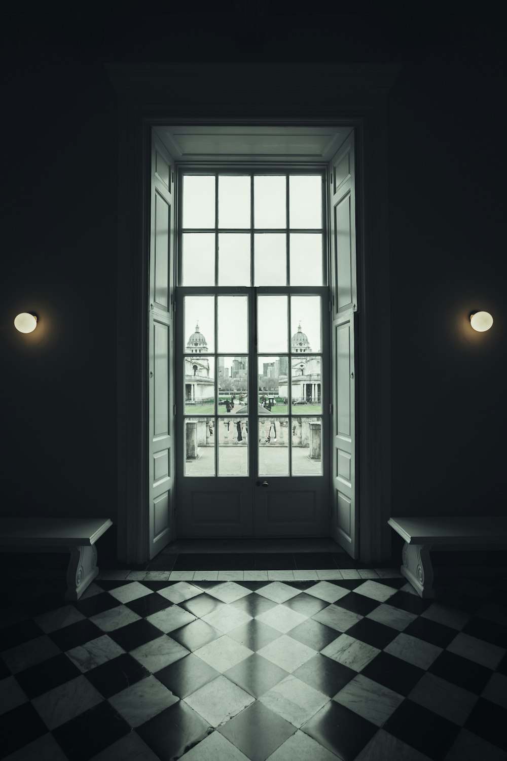 una stanza con un pavimento a scacchi e una grande finestra