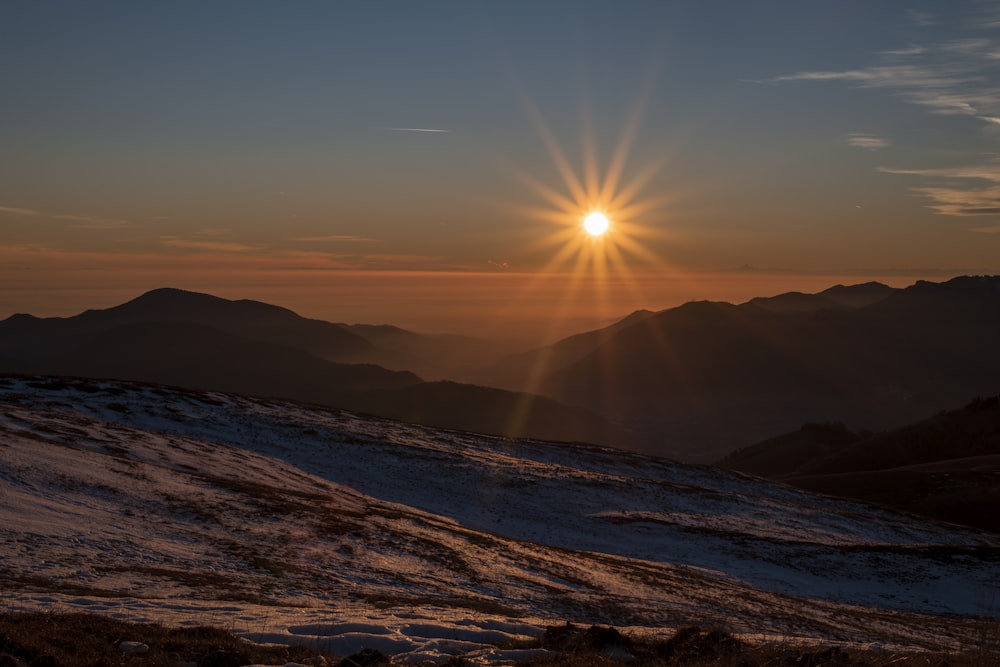 the sun is setting over a mountain range