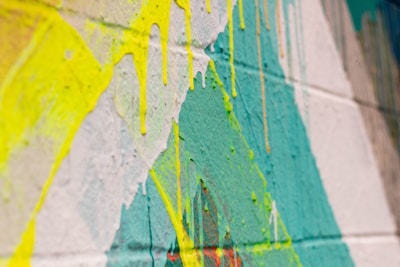 Close-up of paint dripping down a canvas in bright, saturated hues.