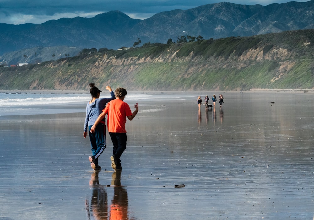 a group of people walking along a beach next to the ocean