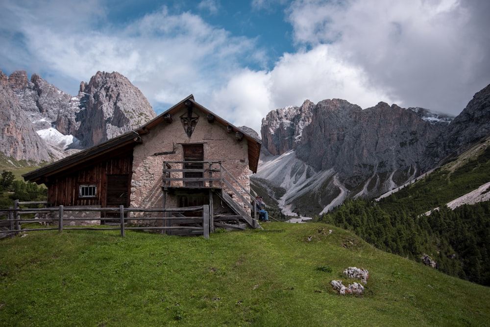 a small building on a grassy hill with mountains in the background