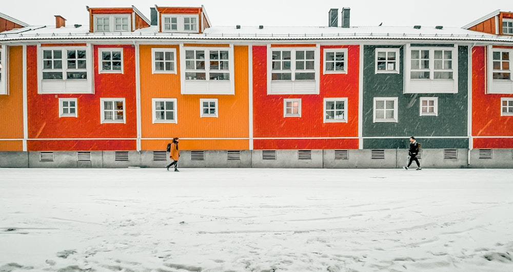 two people walking in front of a multi - colored building