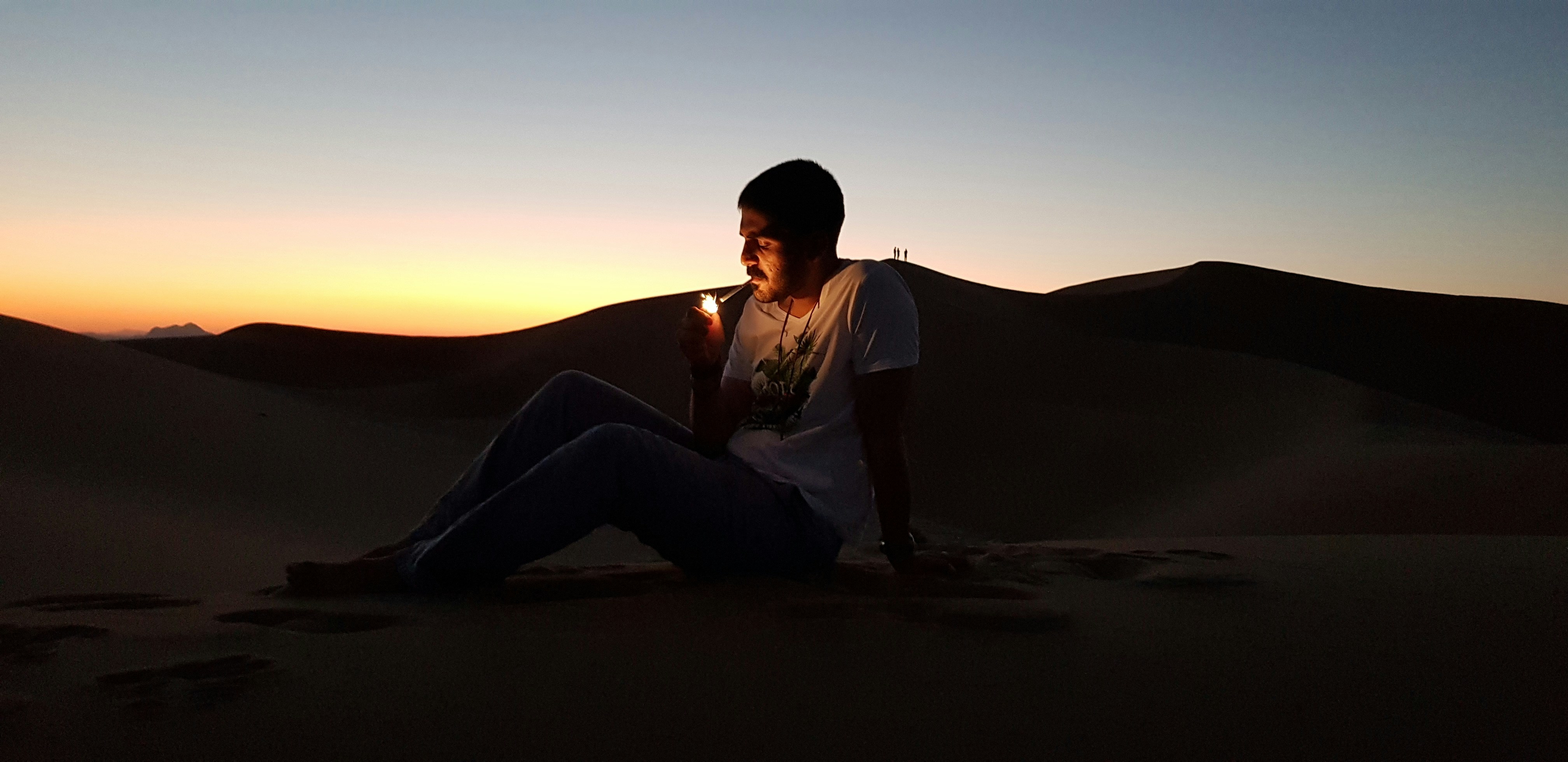 a woman sitting on top of a sand dune