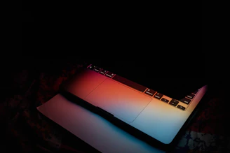 Open laptop with colorful keyboard lighting in a cozy workspace.