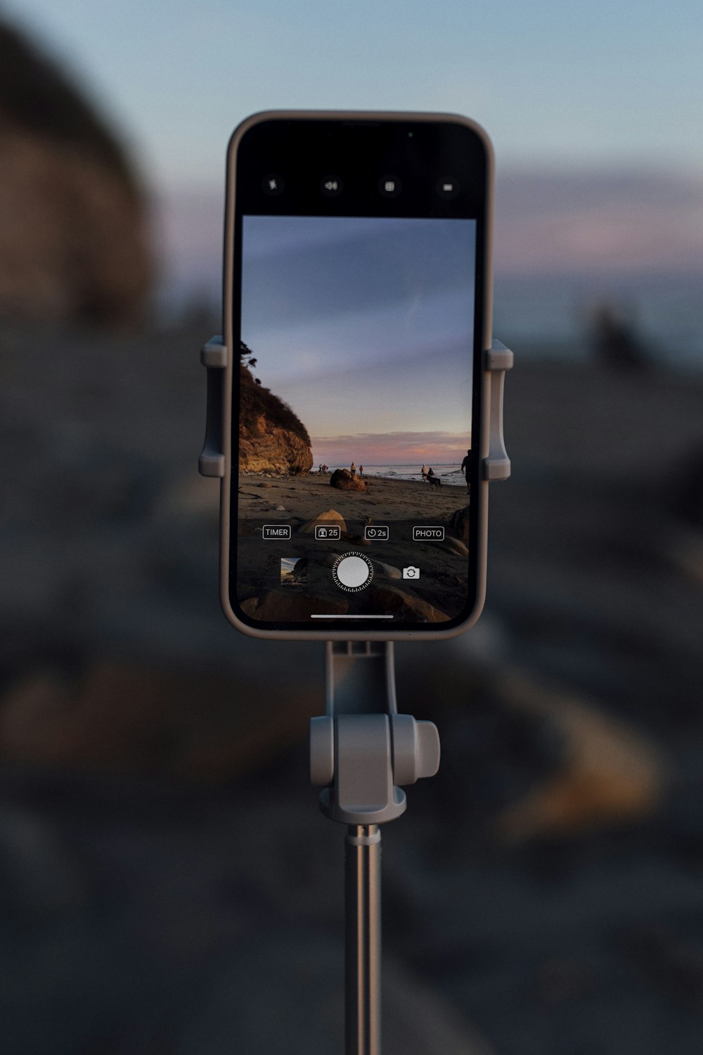 a cell phone on a tripod with a beach in the background