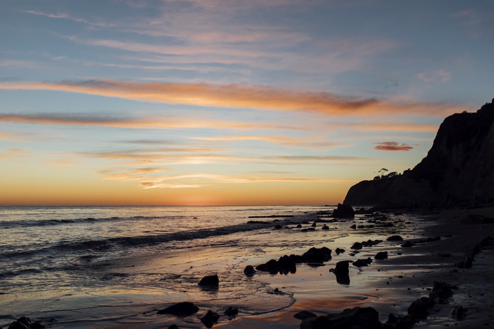 the sun is setting over the ocean on the beach