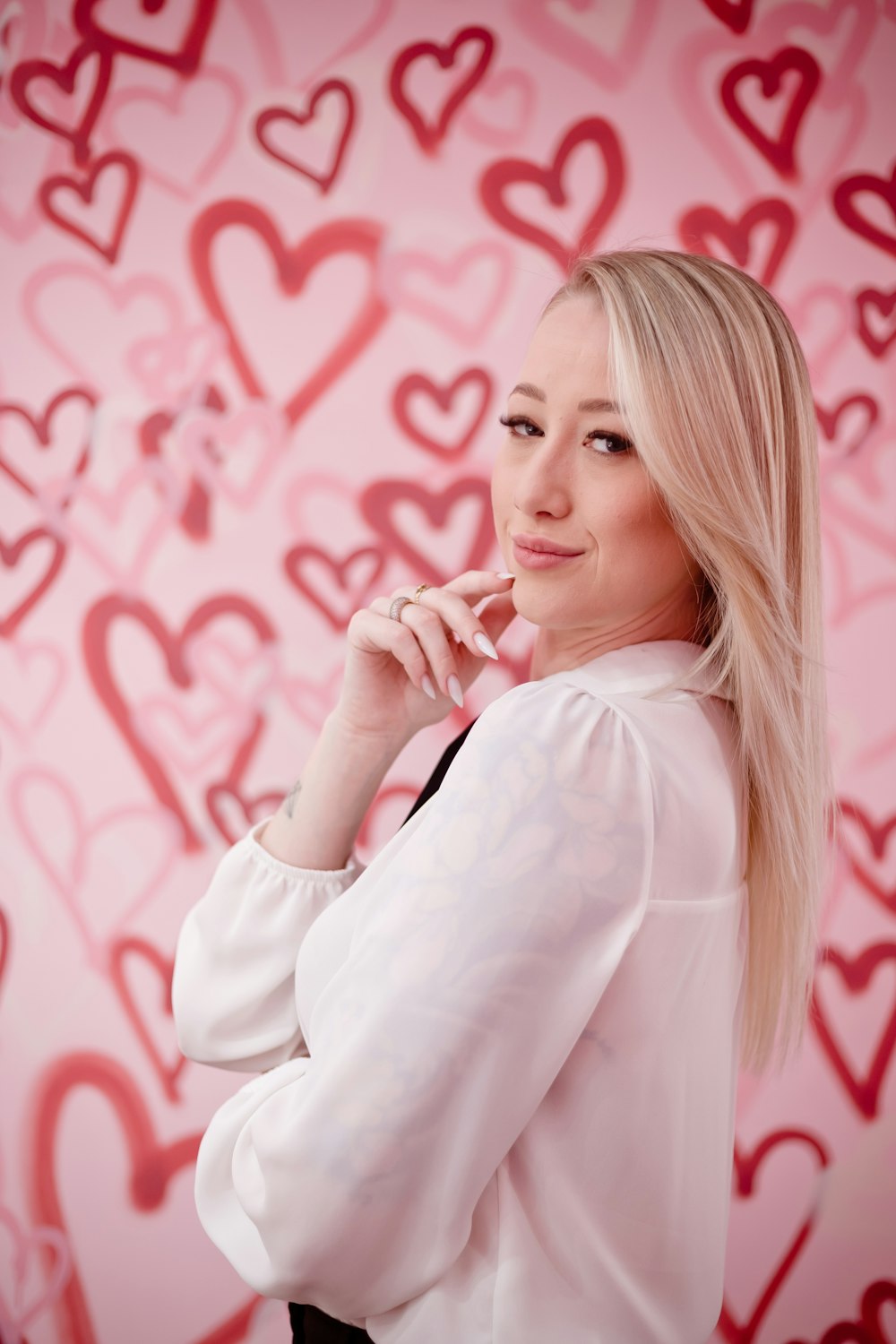 a woman posing for a picture in front of a wall with hearts