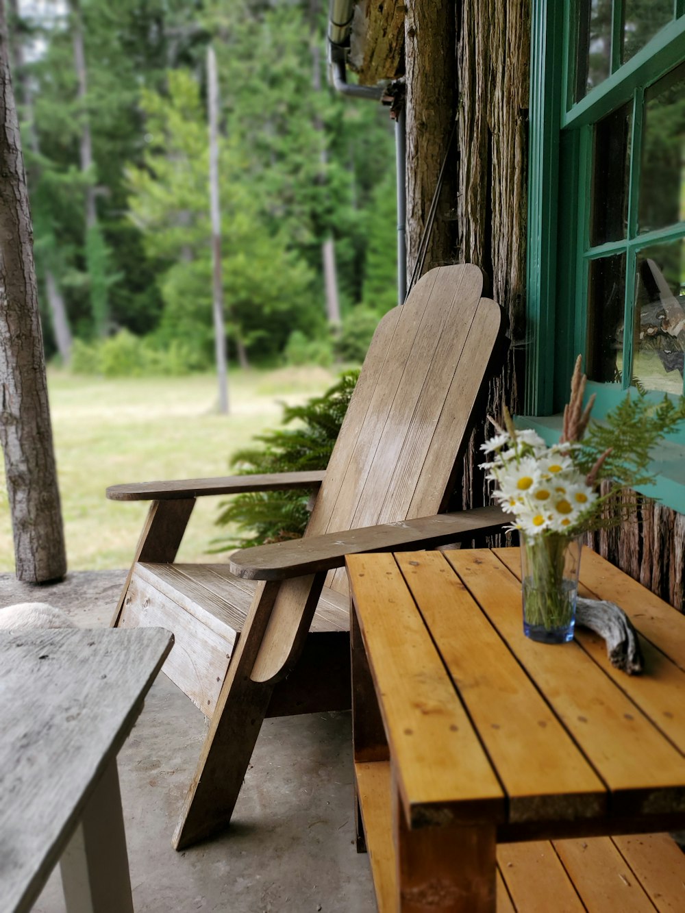 a wooden chair sitting on a porch next to a wooden table