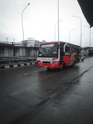 a red and white bus driving down a rain soaked street
