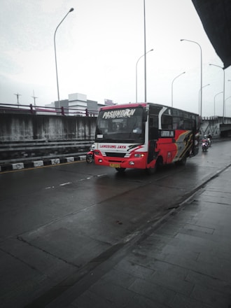 a red and white bus driving down a rain soaked street