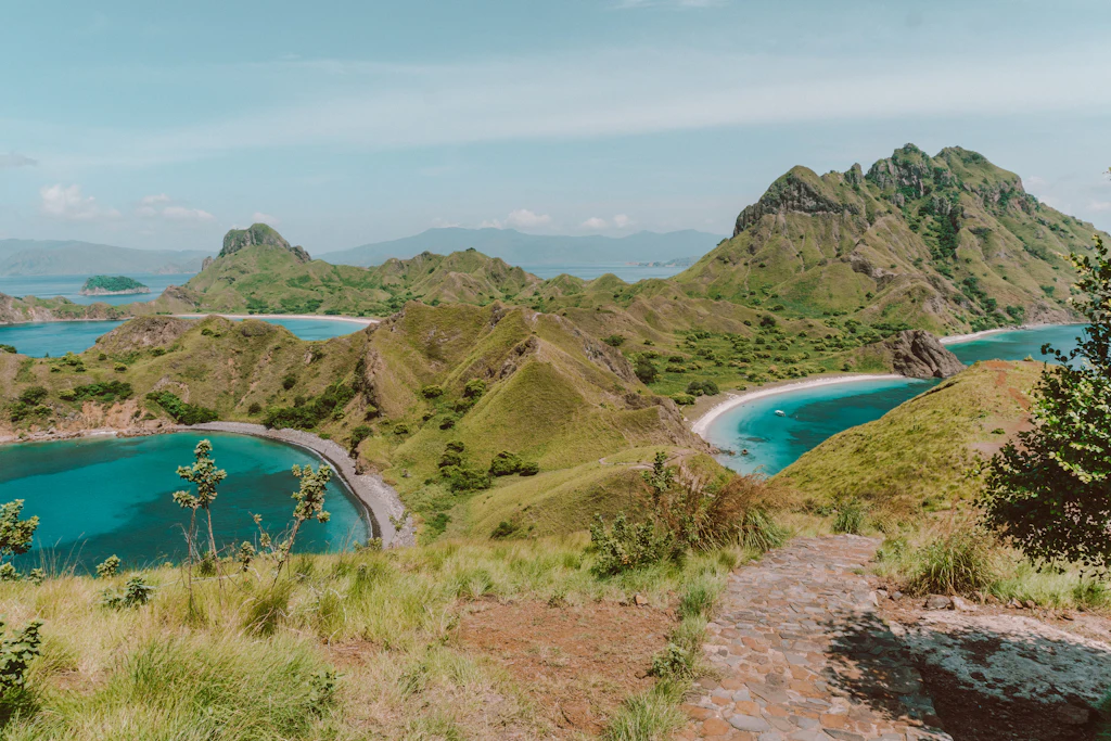 Green ridges and three turquoise bays seen from the stone path on Padar Island, Komodo National Park