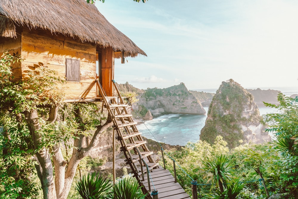 a wooden house with a thatched roof next to a body of water