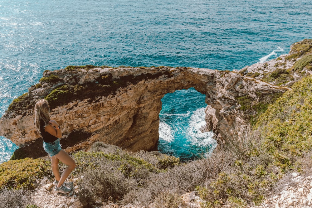 a woman standing on a cliff overlooking the ocean