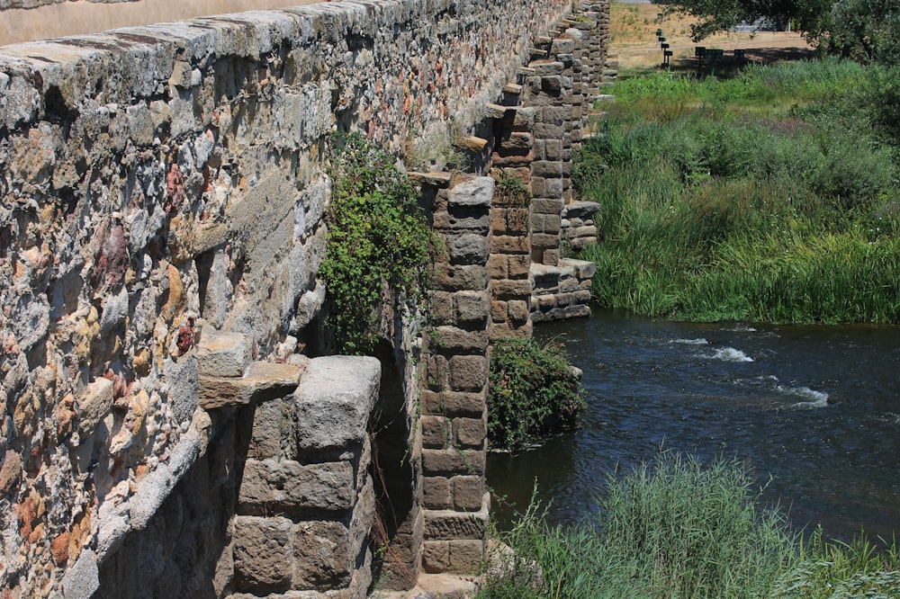 a stone bridge over a river next to a lush green field