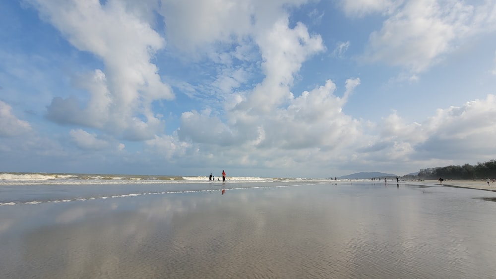 a couple of people standing on top of a sandy beach