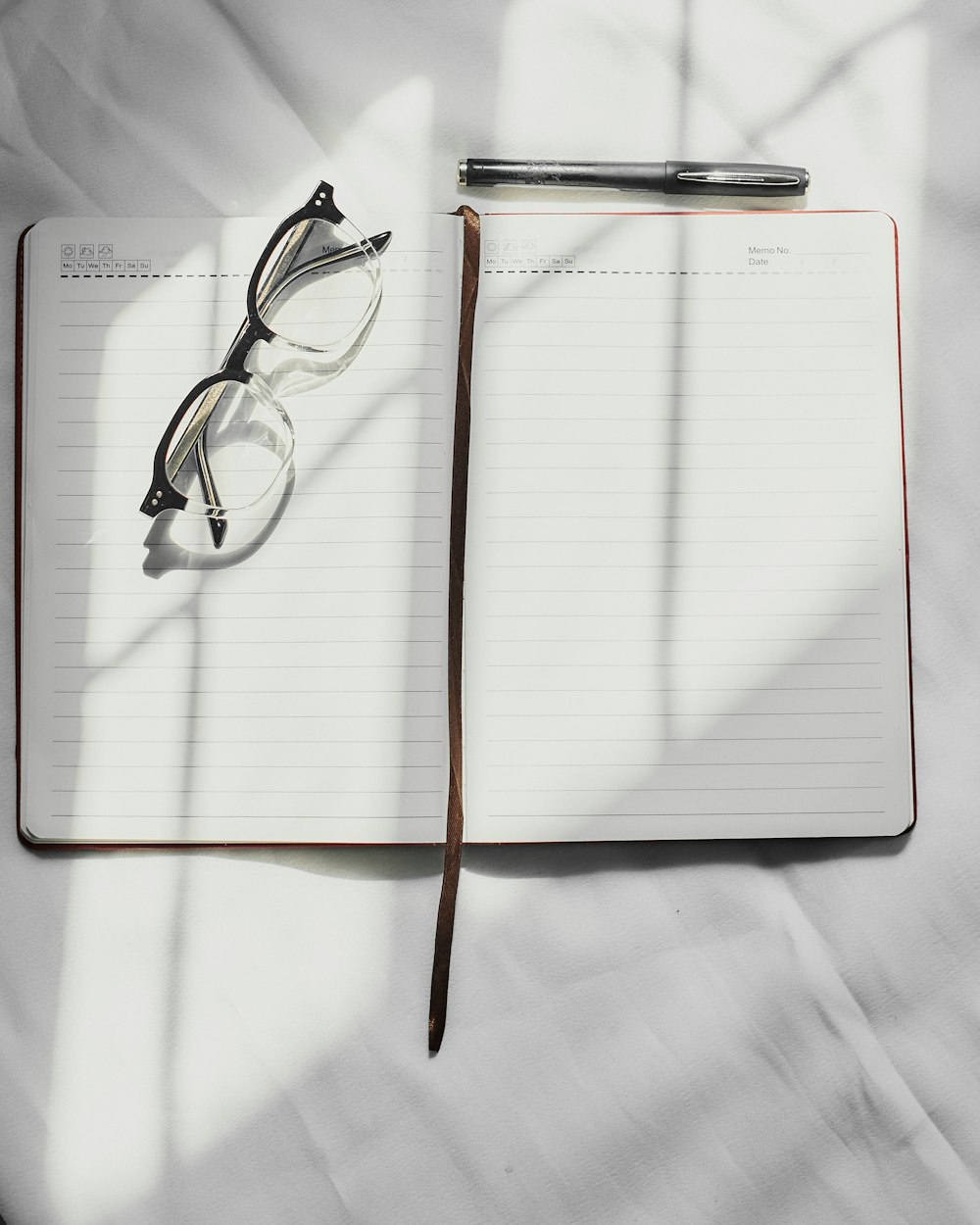 a notebook with a pen and glasses on top of it
