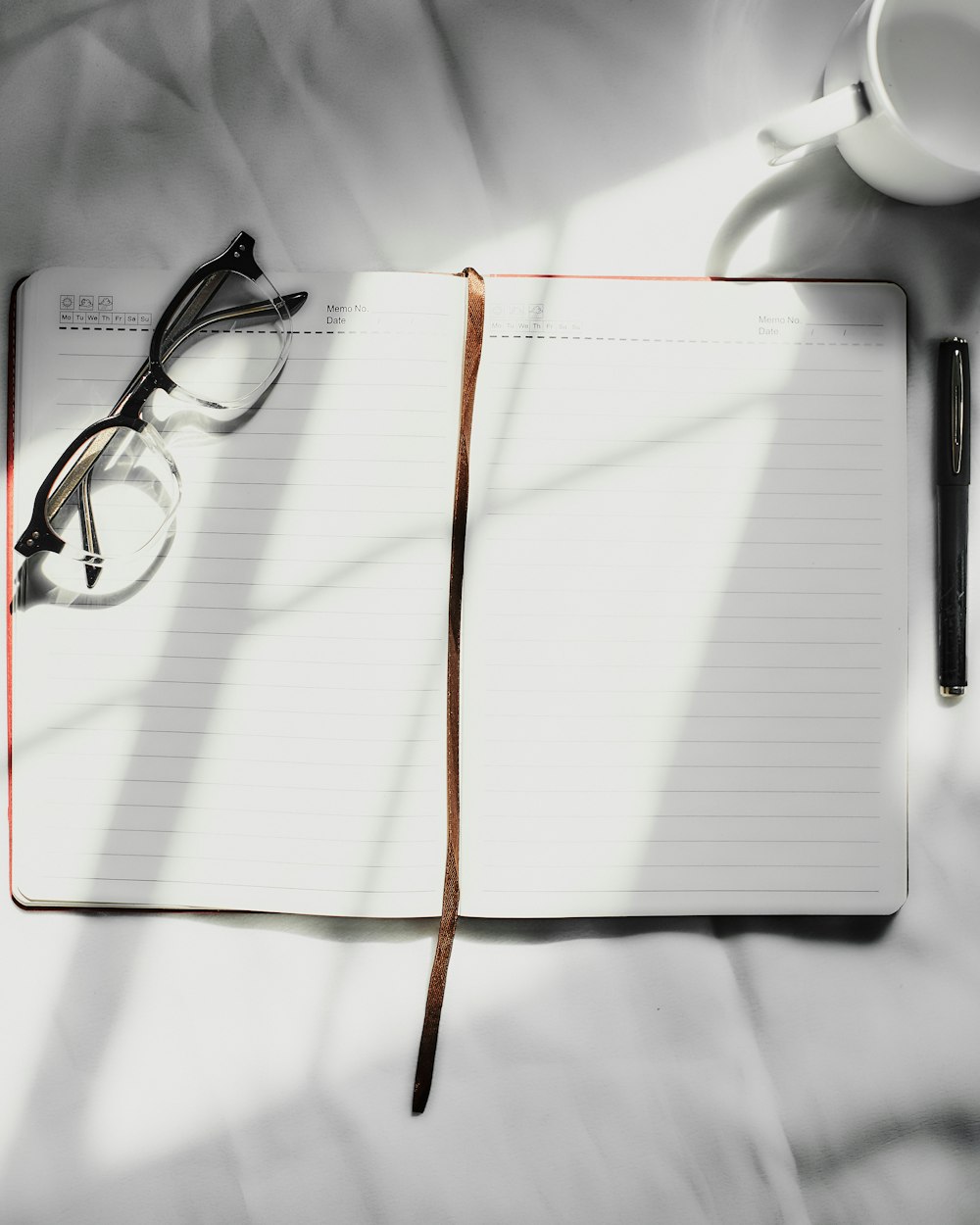 an open notebook with a pair of glasses on top of it