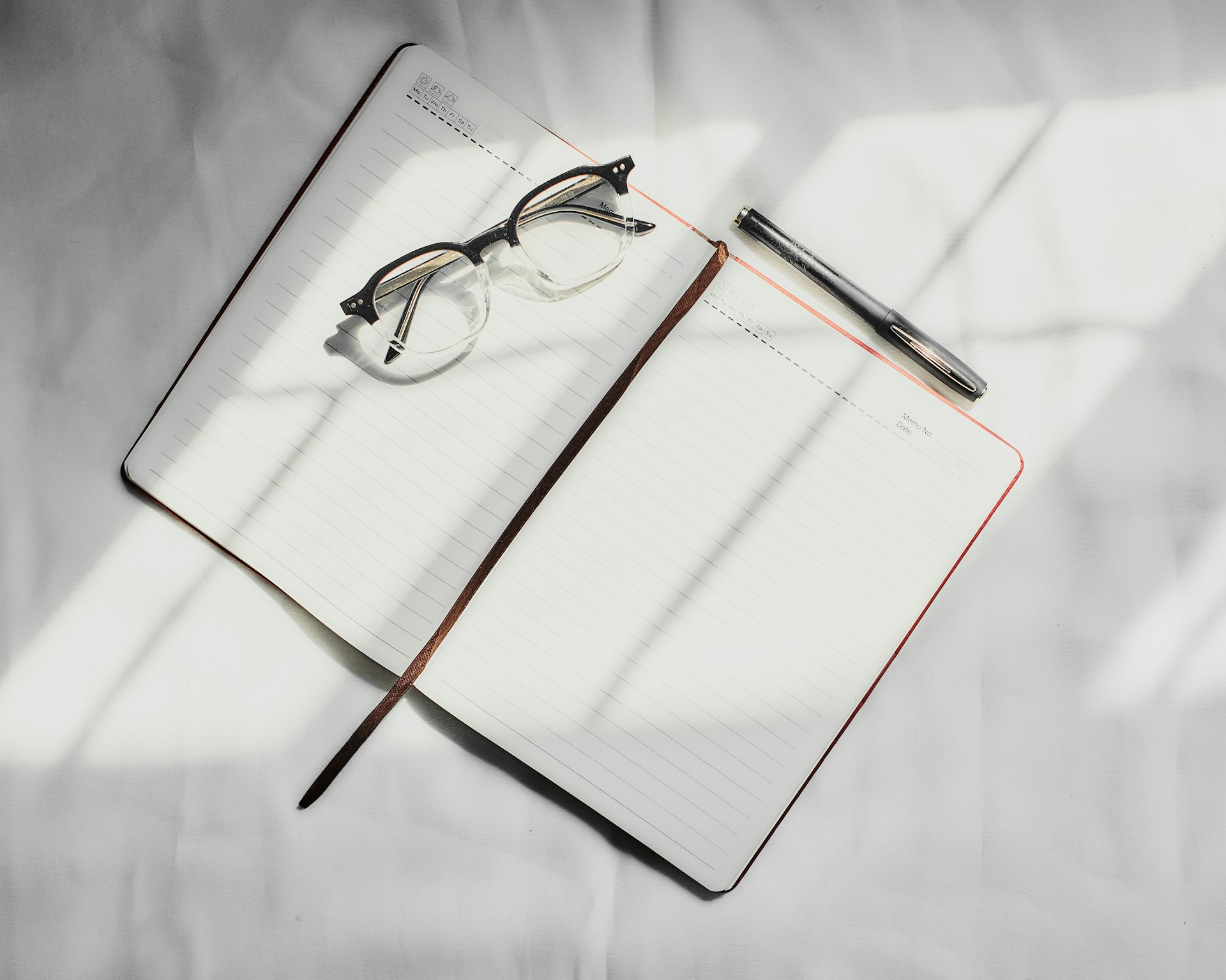 a notebook with a pen and glasses on top of it