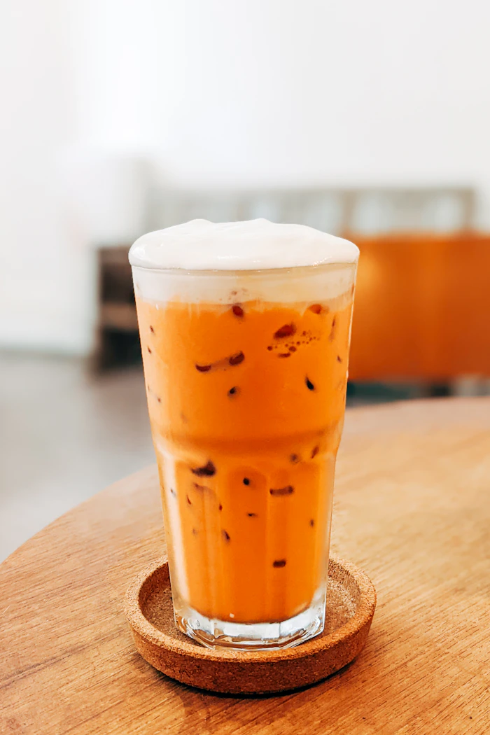 Glass of bright orange Thai iced tea with milk