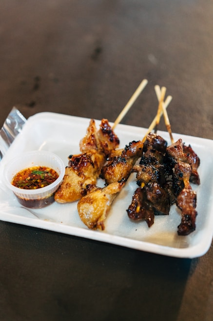 An elegant half tray filled with spicy suya skewers, garnished with fresh onions and tomatoes.