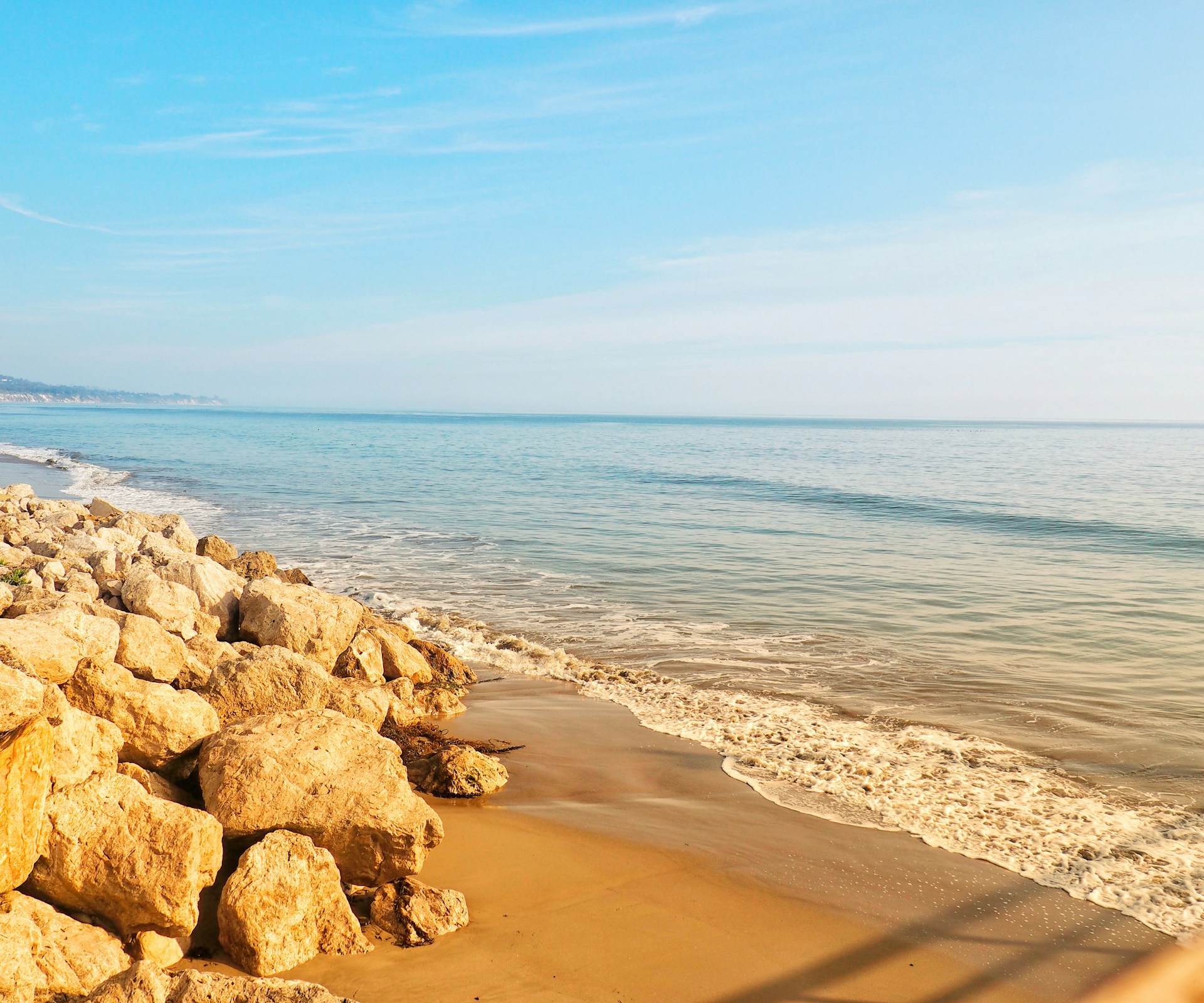 a sandy beach with rocks and a body of water