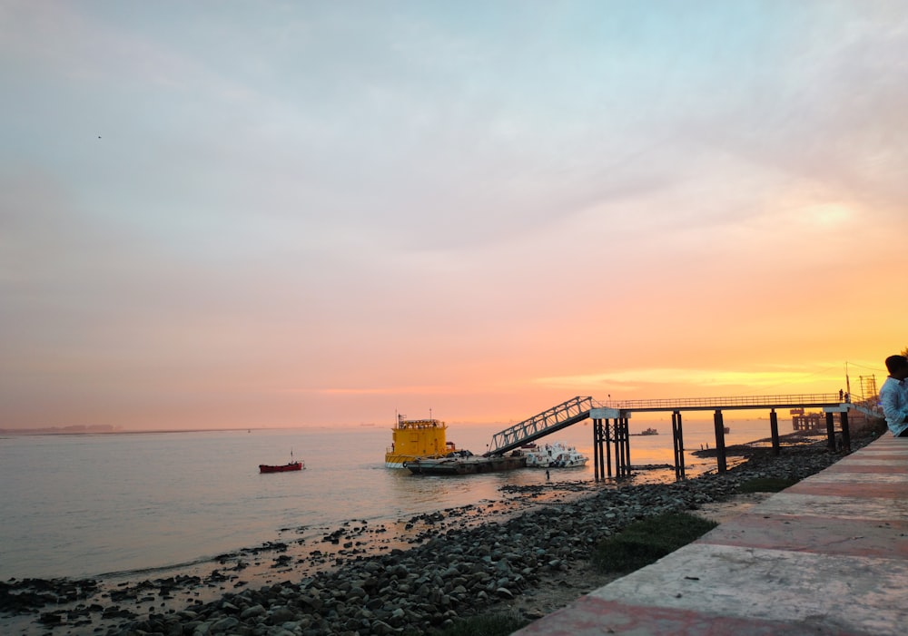 a person sitting on a dock watching the sunset