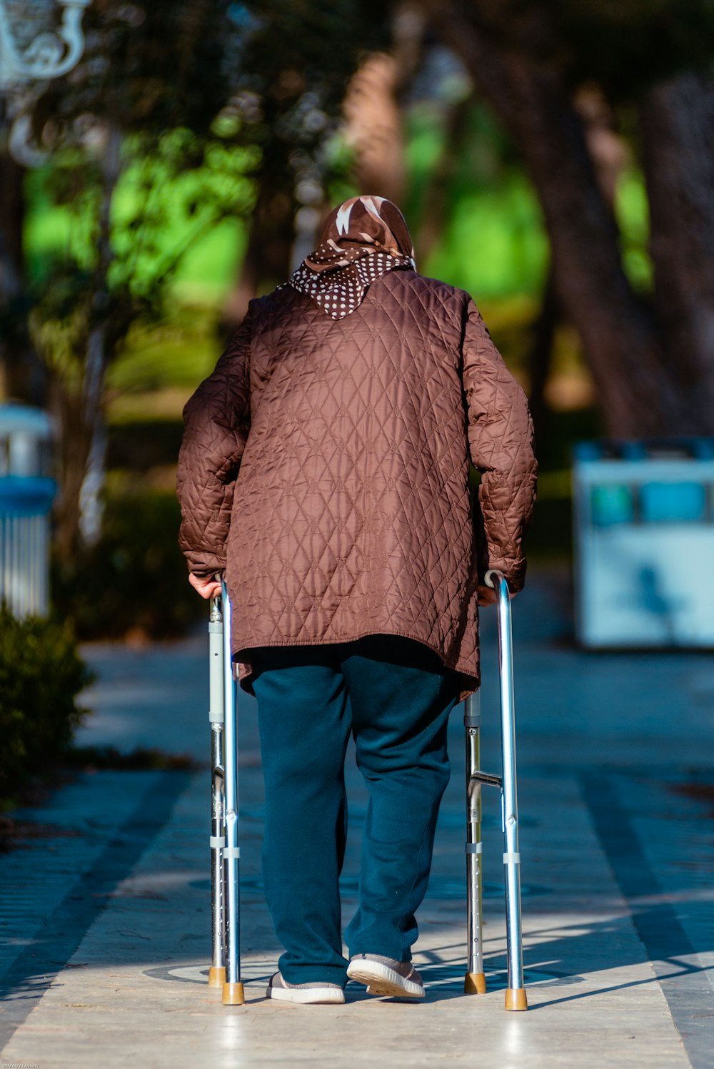 a person with a walker walking down a sidewalk
