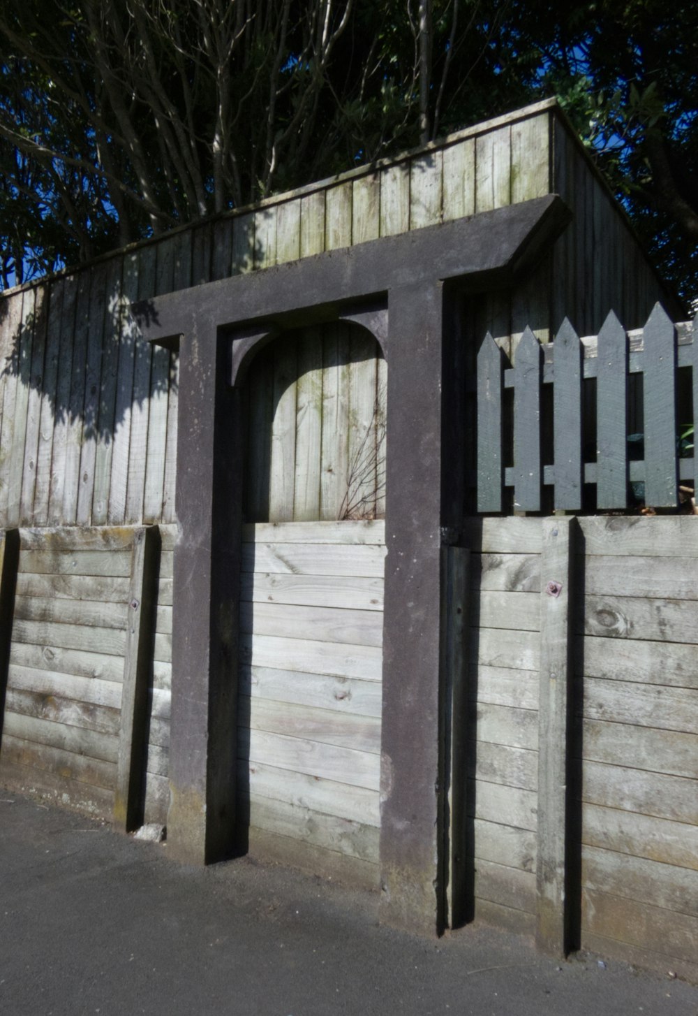 a wooden structure with a door and a fence around it