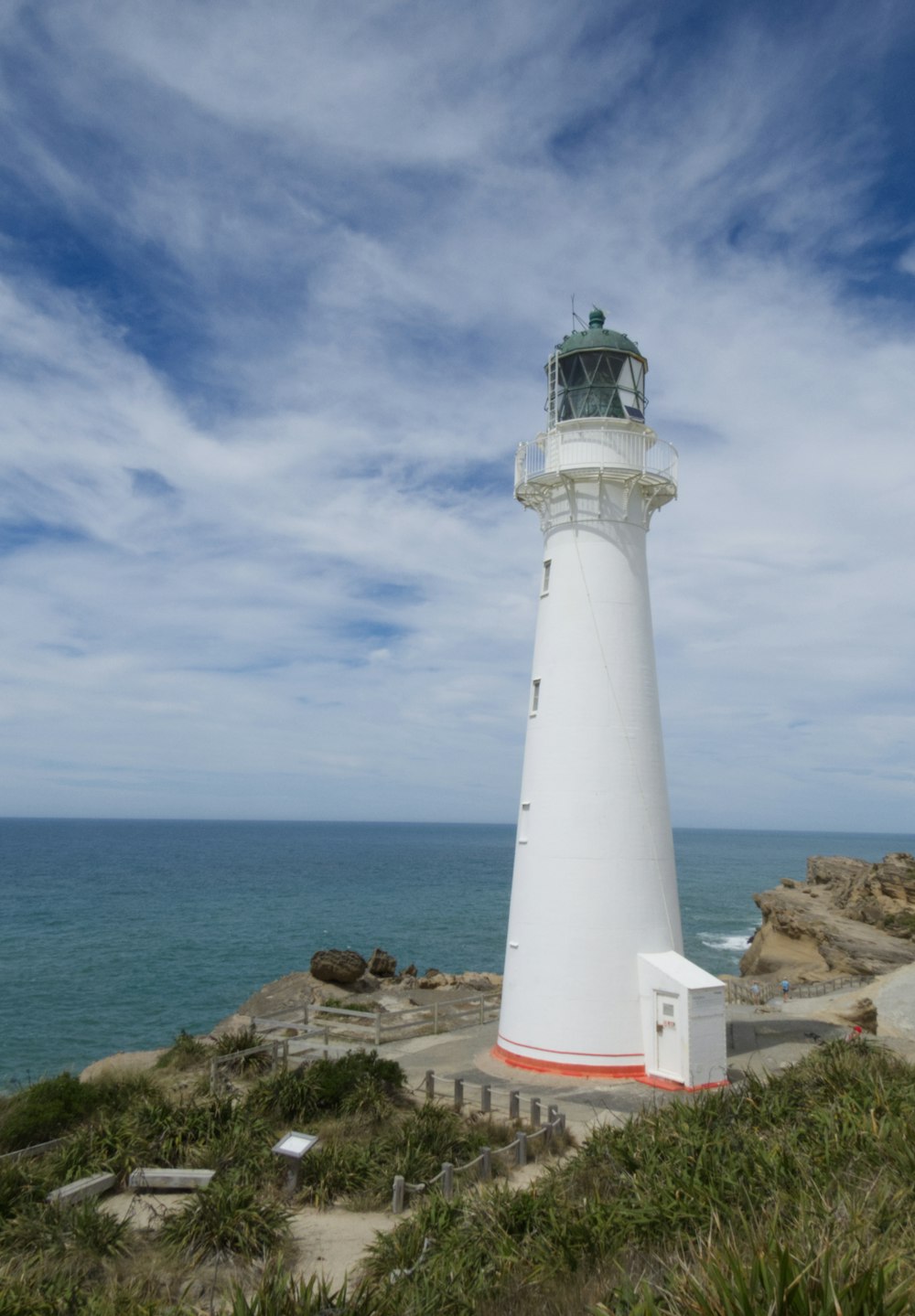 a white light house sitting on top of a hill next to the ocean