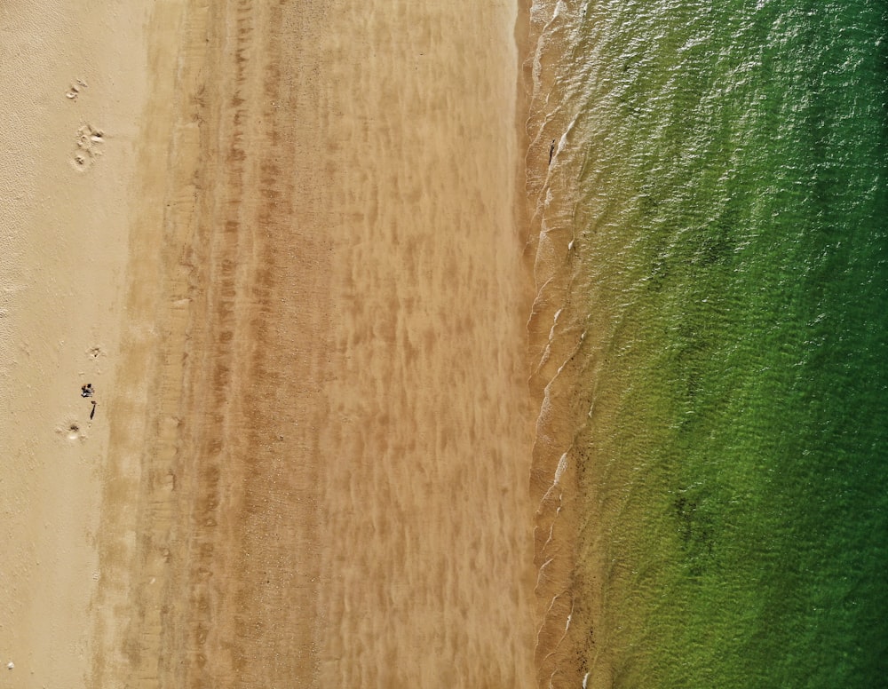 an aerial view of a sandy beach with green water