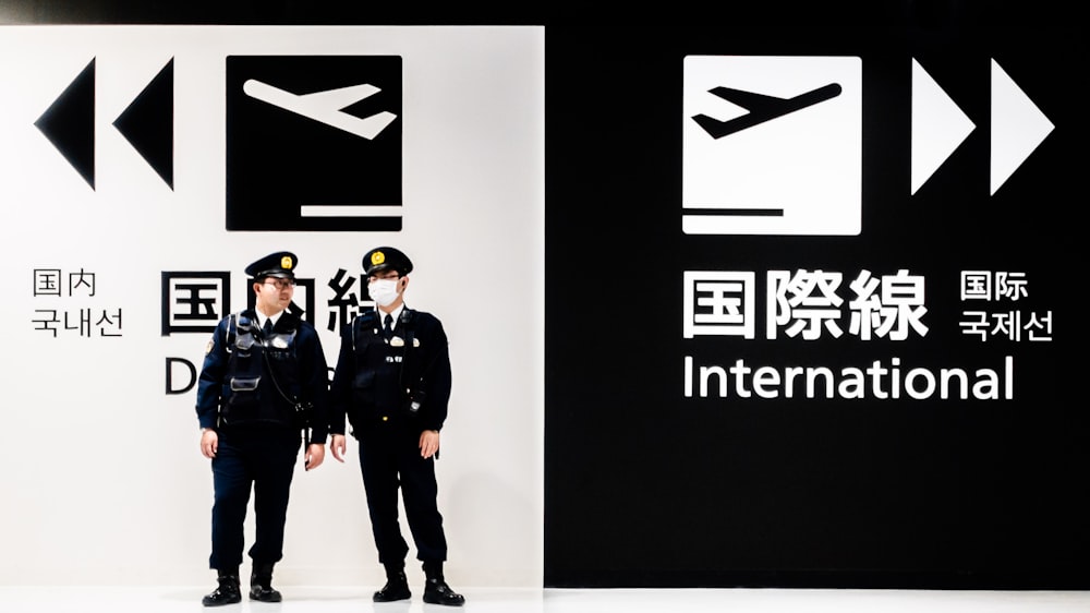 two police officers standing in front of a black and white sign