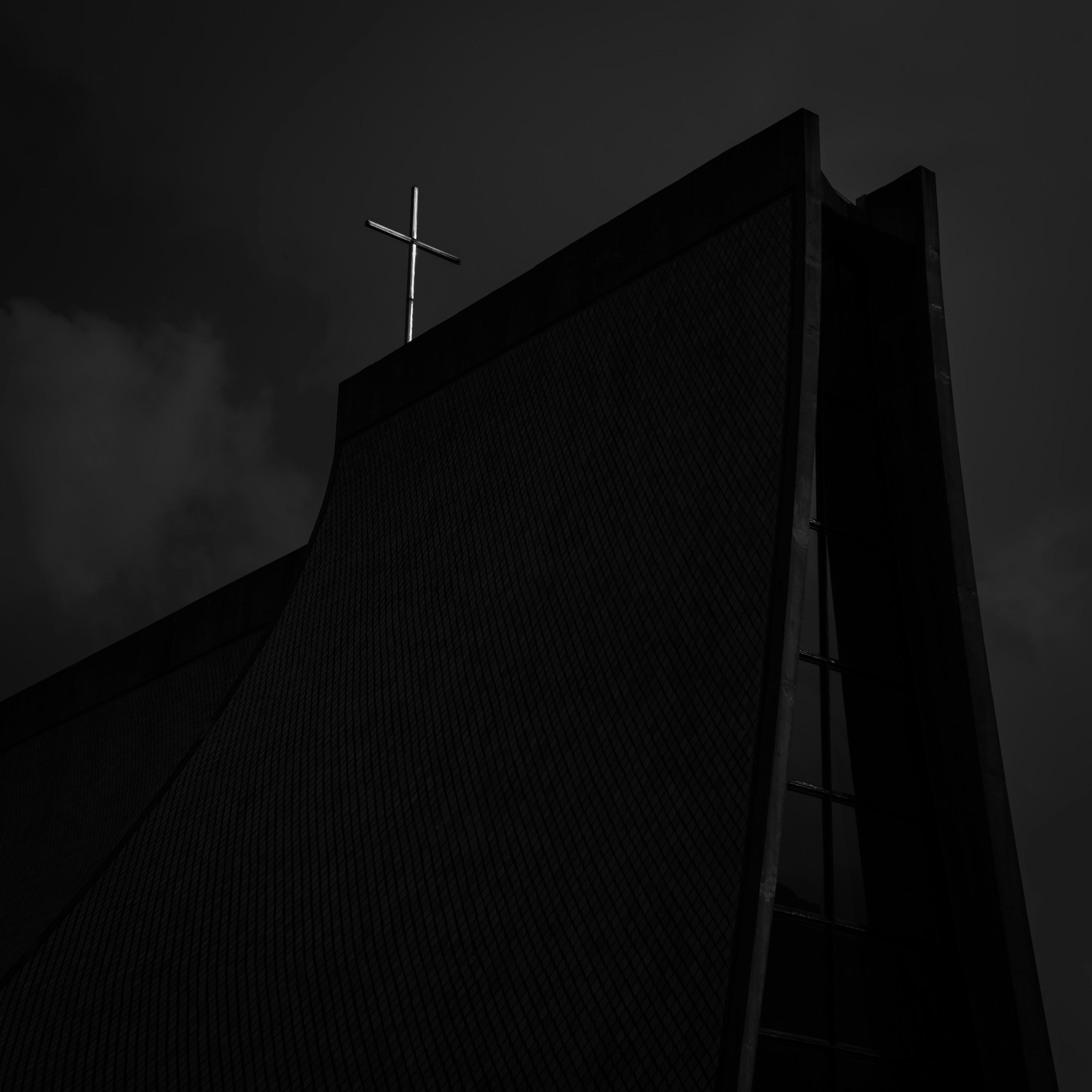 a black and white photo of a cross on top of a building