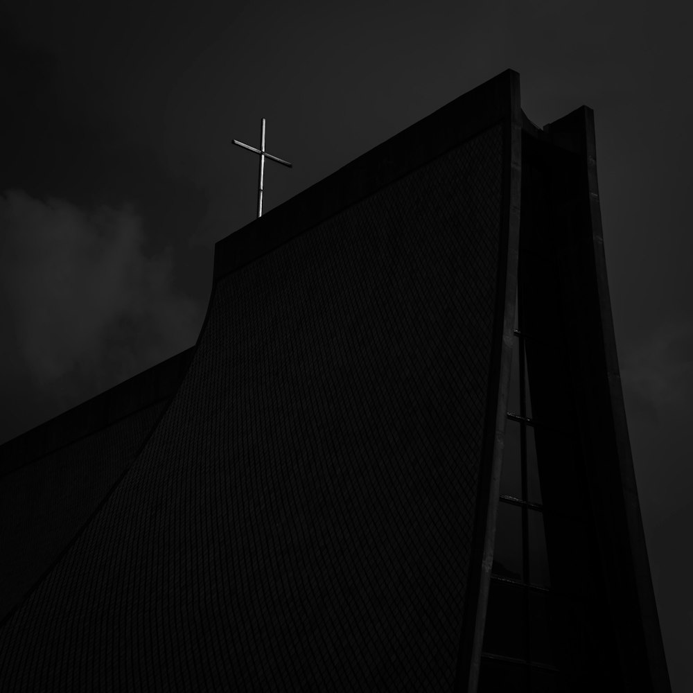 a black and white photo of a cross on top of a building