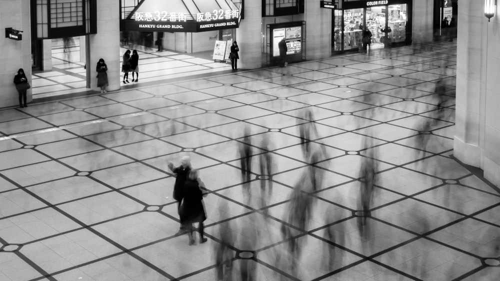 a black and white photo of people walking in a mall