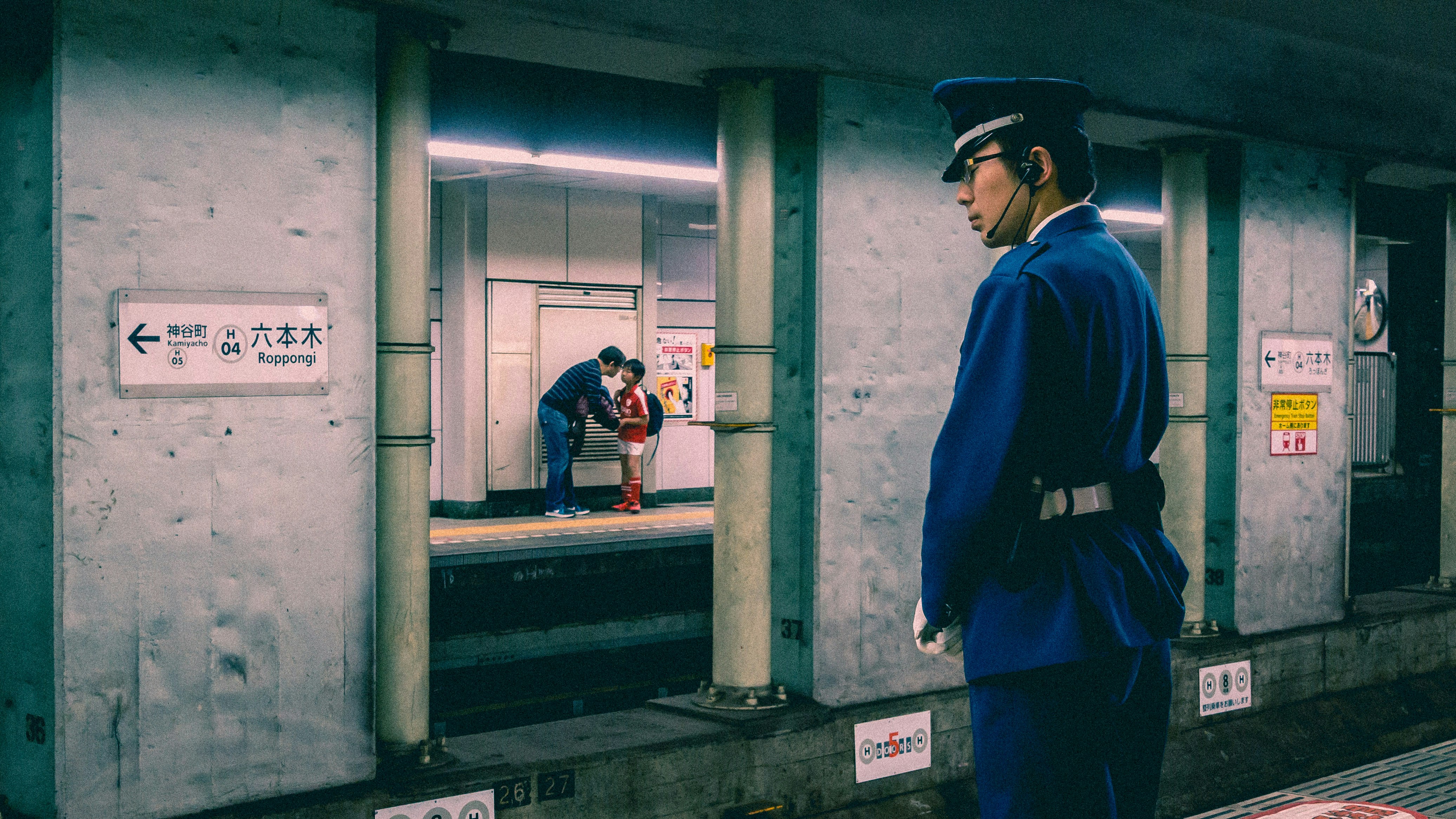 a man in a blue uniform waiting for a train